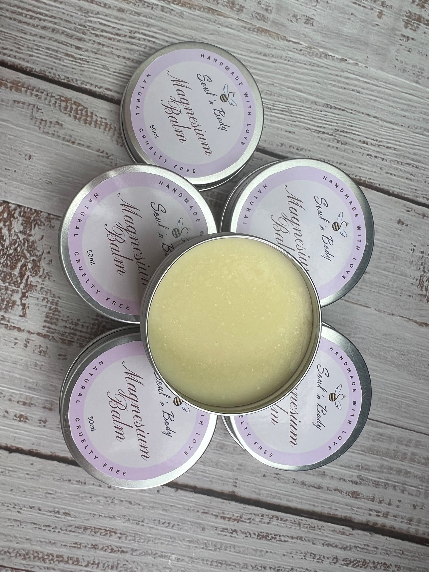 Five tins of 'Magical Balm' on a wooden surface