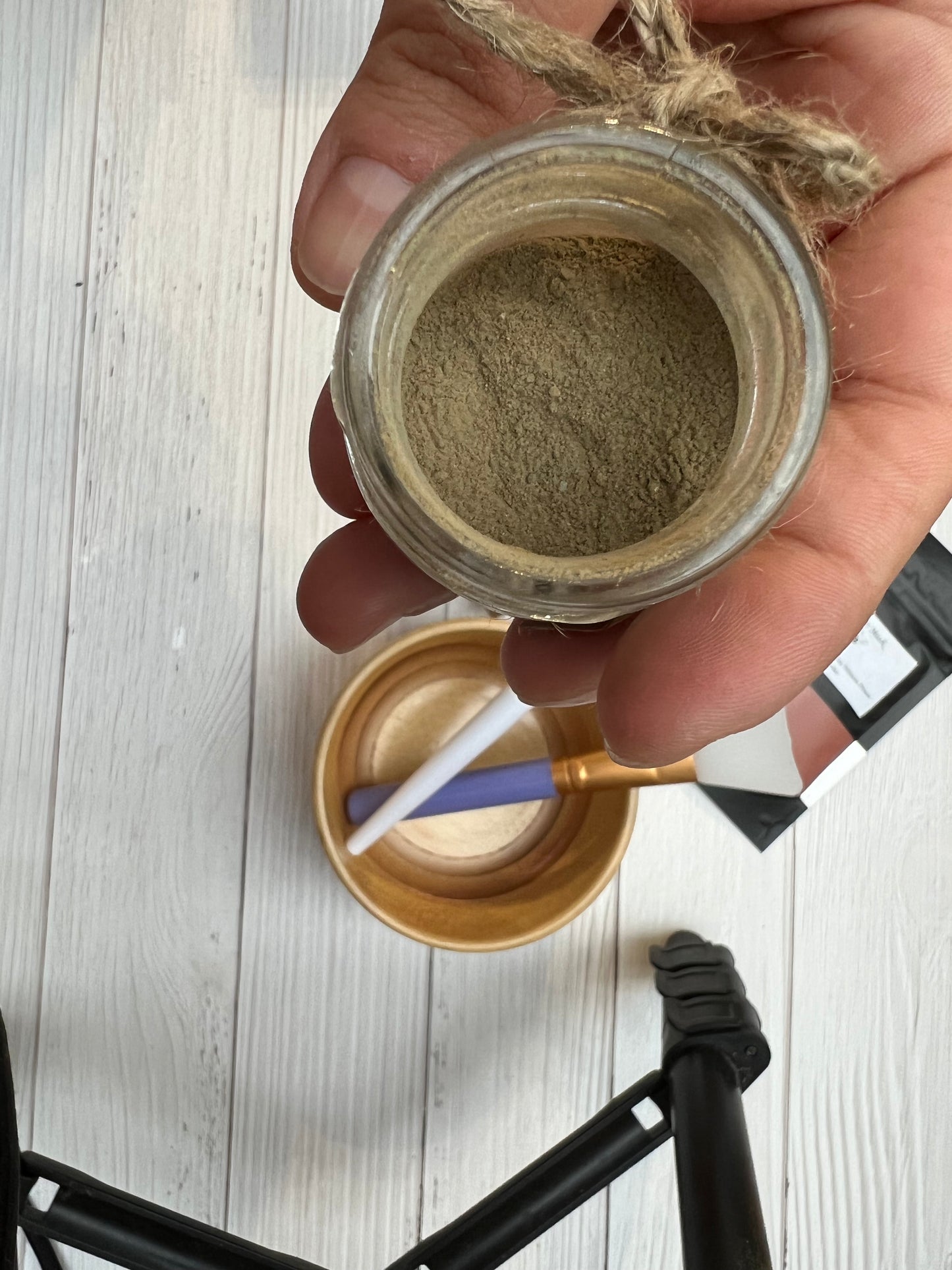 Hand holding a jar of natural clay face mask powder.