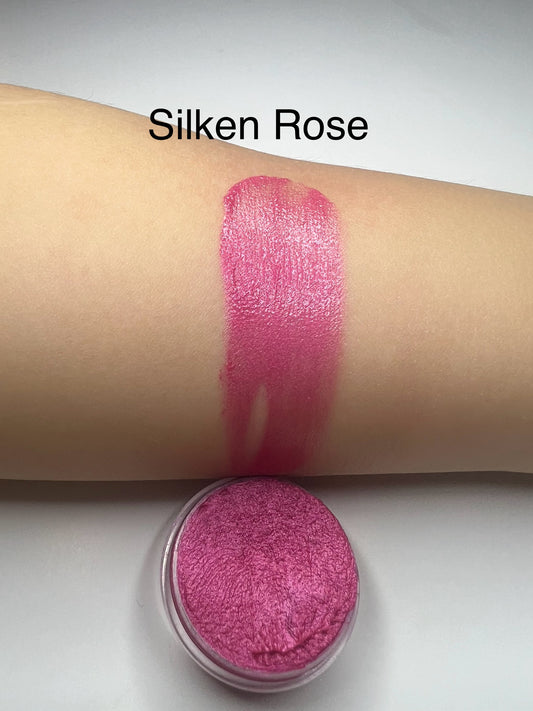 Pink makeup product swatch on arm with 'Silken Rose' text