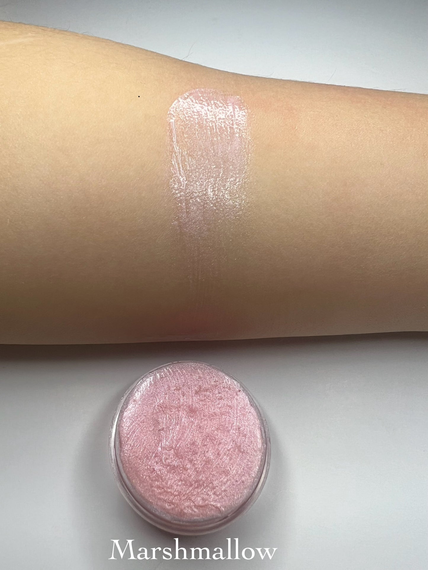 Marshmallow – “Handmade soft pink shimmer lip balm in a tin with a glossy swatch on skin, labeled Marshmallow.