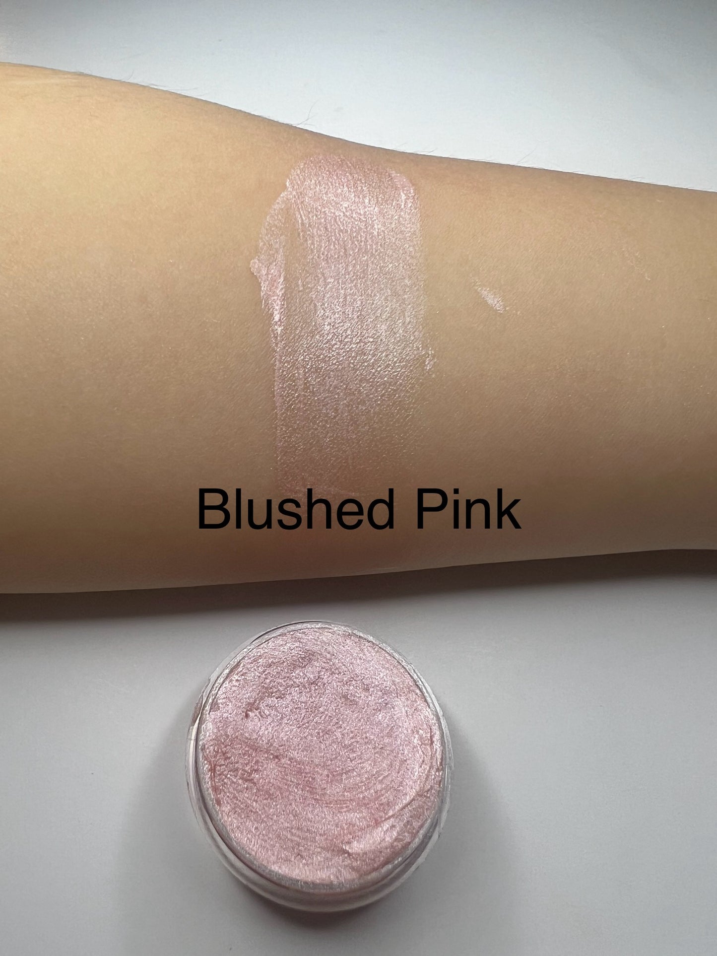 Blushed Pink ā āHandmade pale blush pink shimmer lip balm in a tin with a swatch on skin, labeled Blushed Pink.