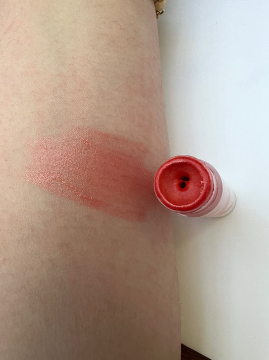 Coral red lip balm swatch on skin — smooth, sheer tint with natural glow.