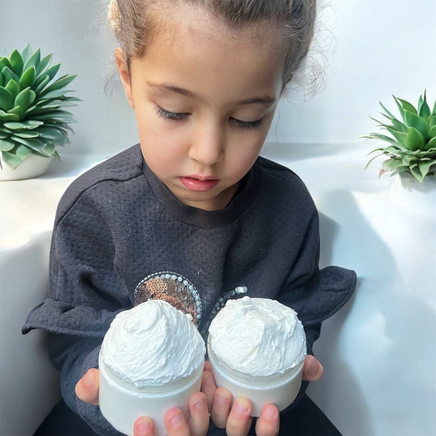 Child holding jar of natural body butter for kids