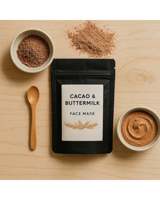 Cacao & Buttermilk Face Mask jar placed on a flat surface with a wooden spoon, a small bowl of powder, and cacao pieces around it.