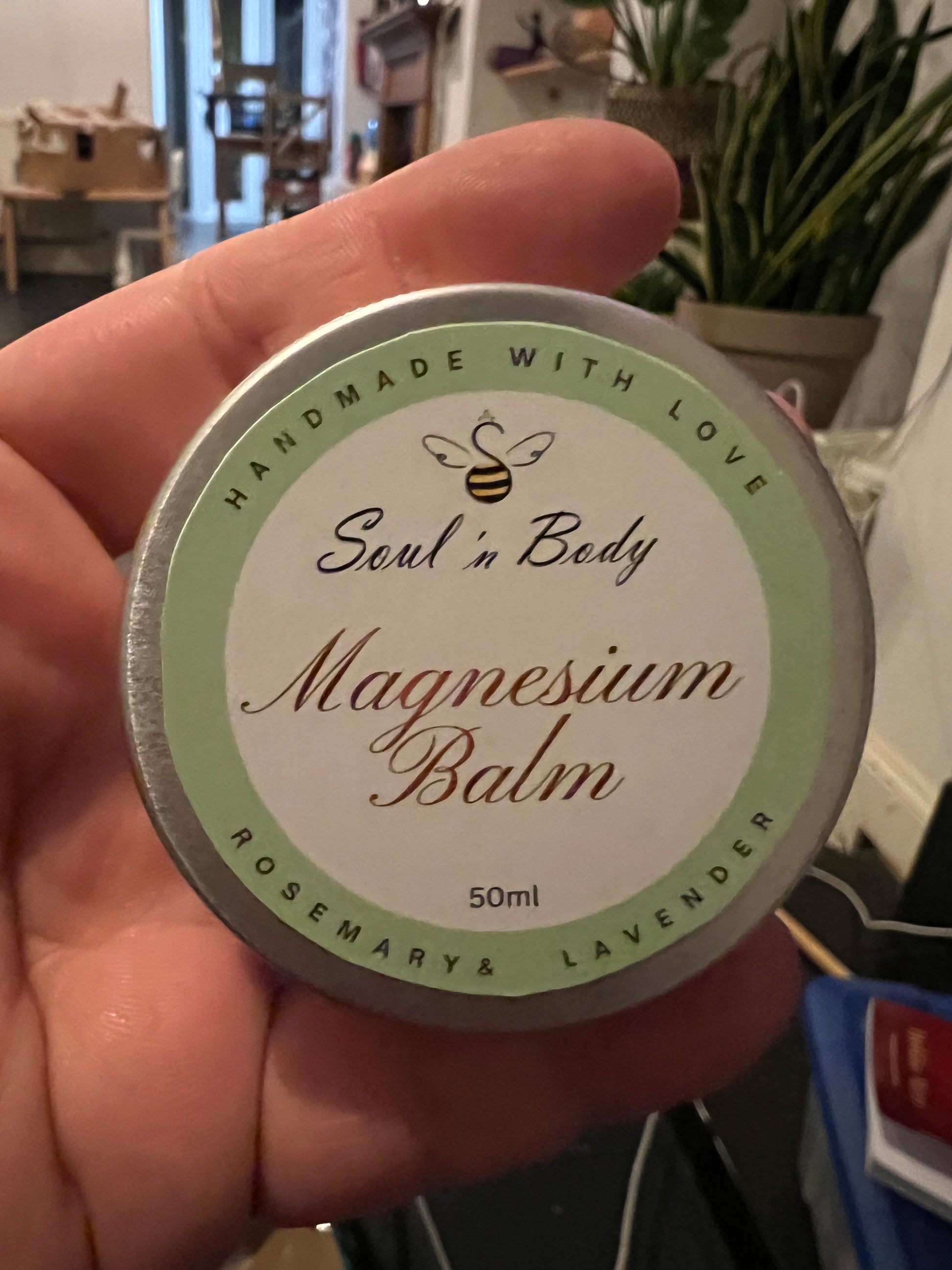 Hand holding a container of 'Soul n Body' magnesium balm with a green and white label.