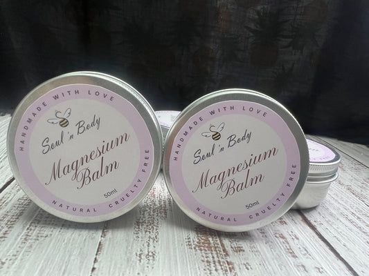 Two tins of Magnesium Balm with a visible brand logo on a wooden surface.
