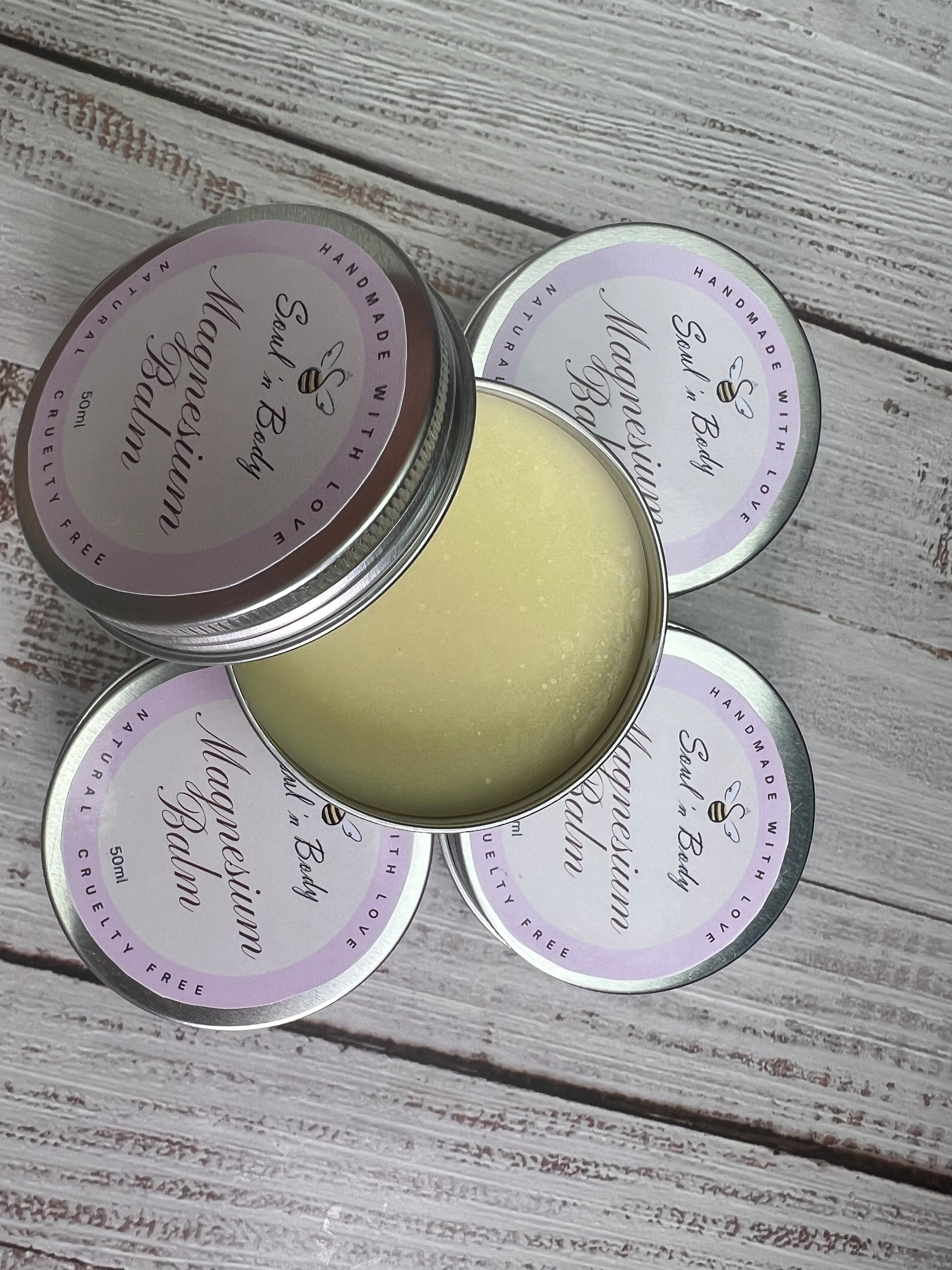 Open tin of magnesium balm with closed tins on a wooden surface