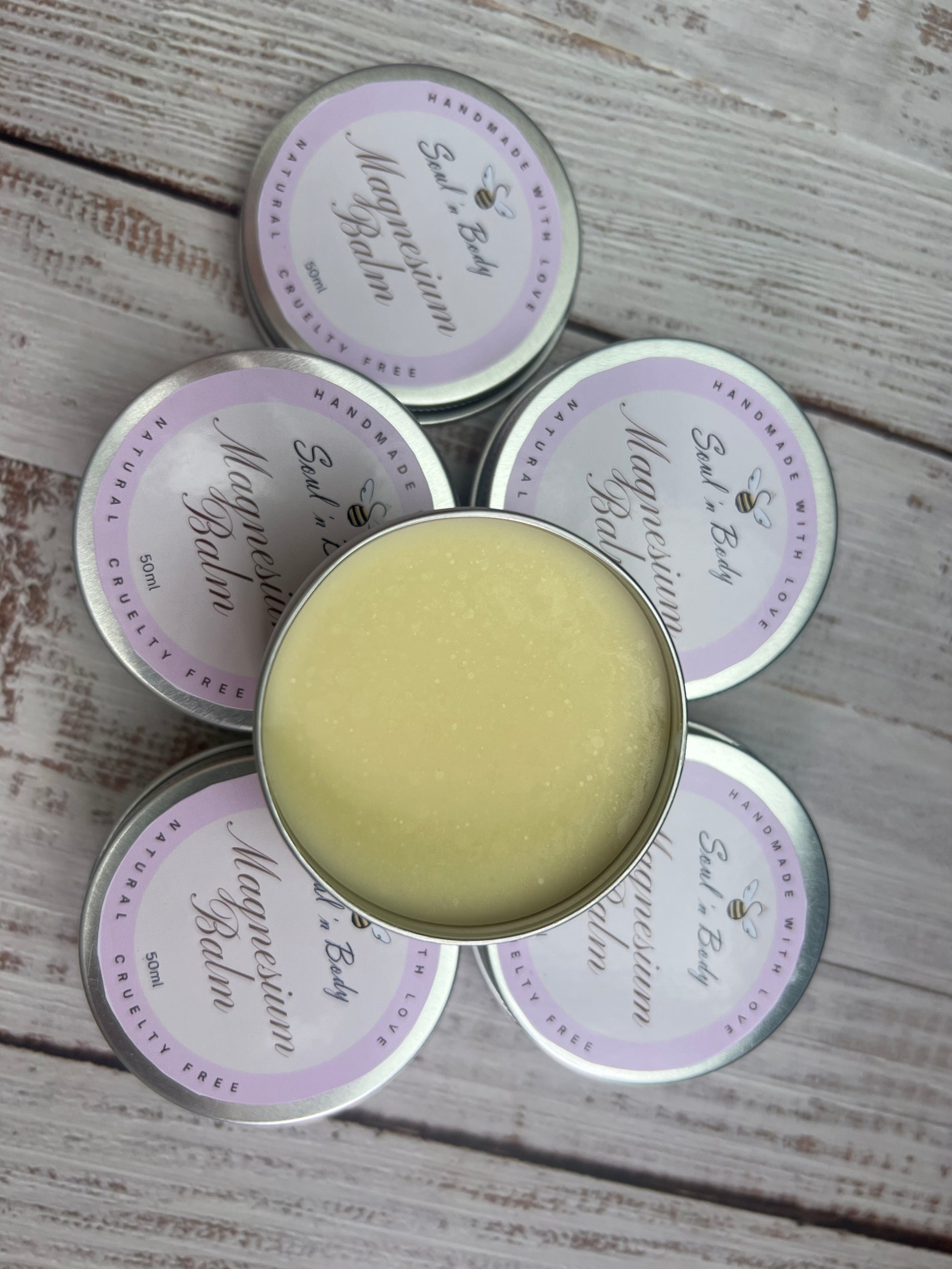 Five tins of magnesium balm on a wooden surface