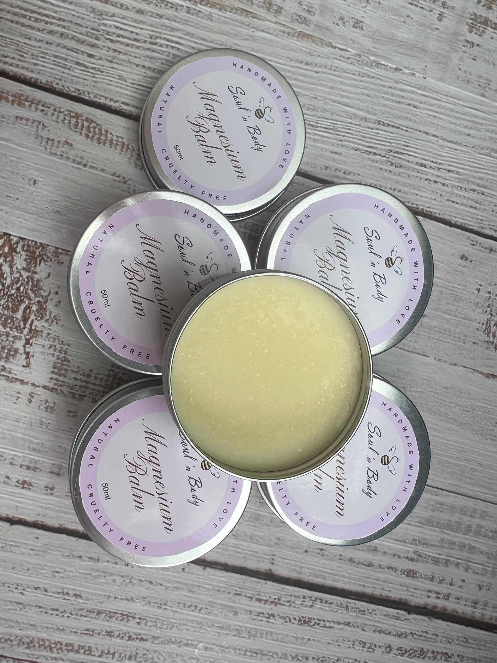 Five tins of 'Magical Balm' on a wooden surface