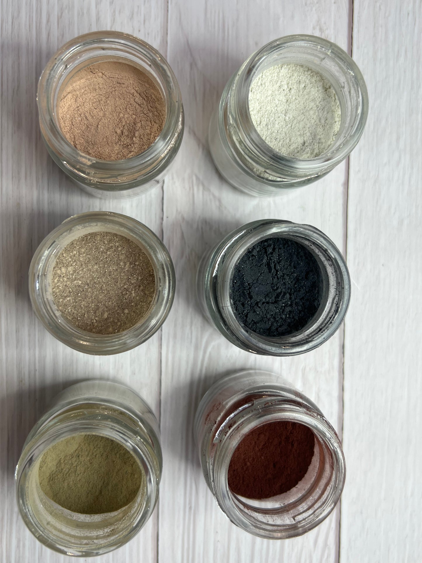 Natural clay and rosehip face and hand mask with ingredients laid out on wooden surface.