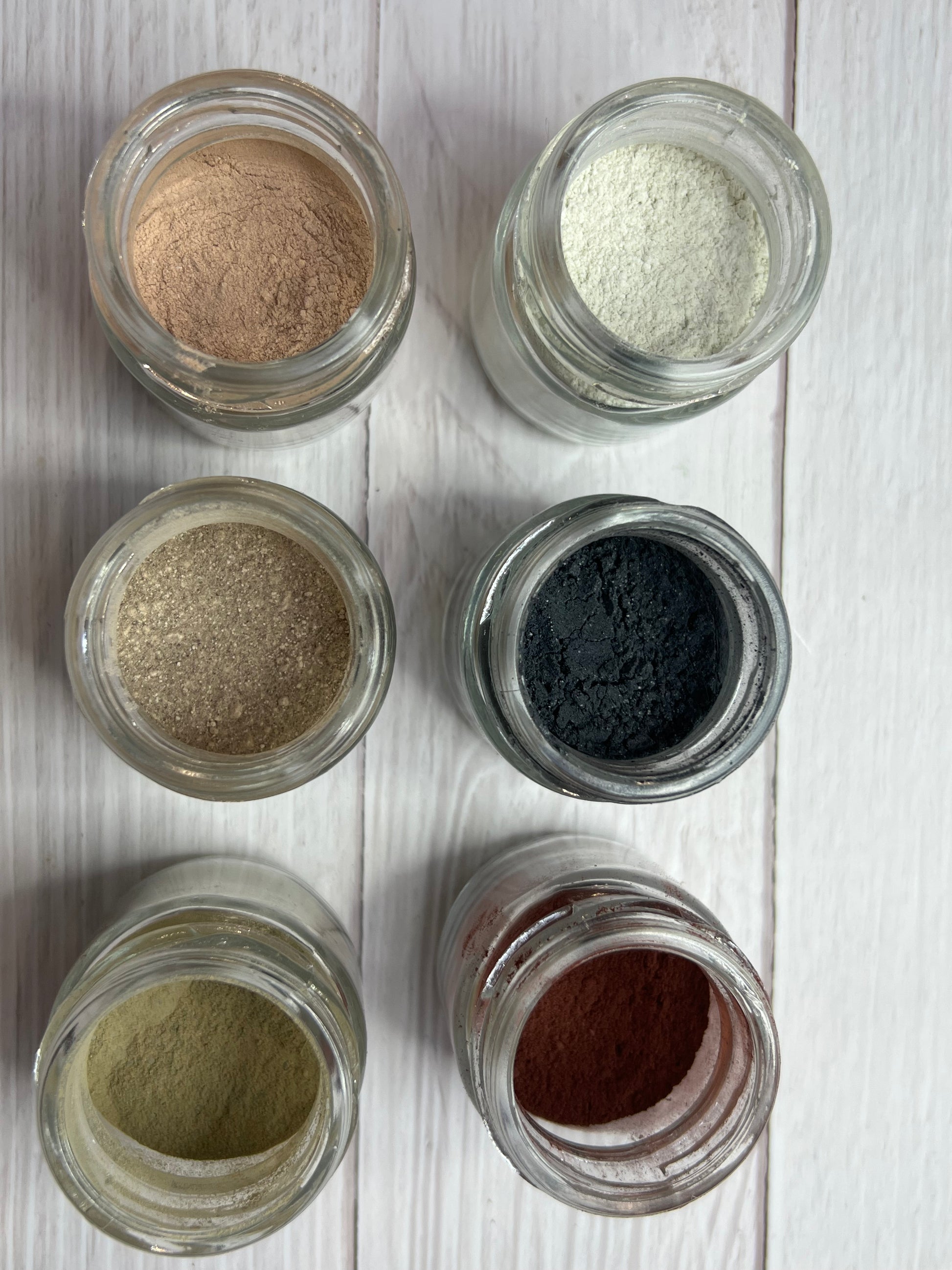 Natural clay and rosehip face and hand mask with ingredients laid out on wooden surface.