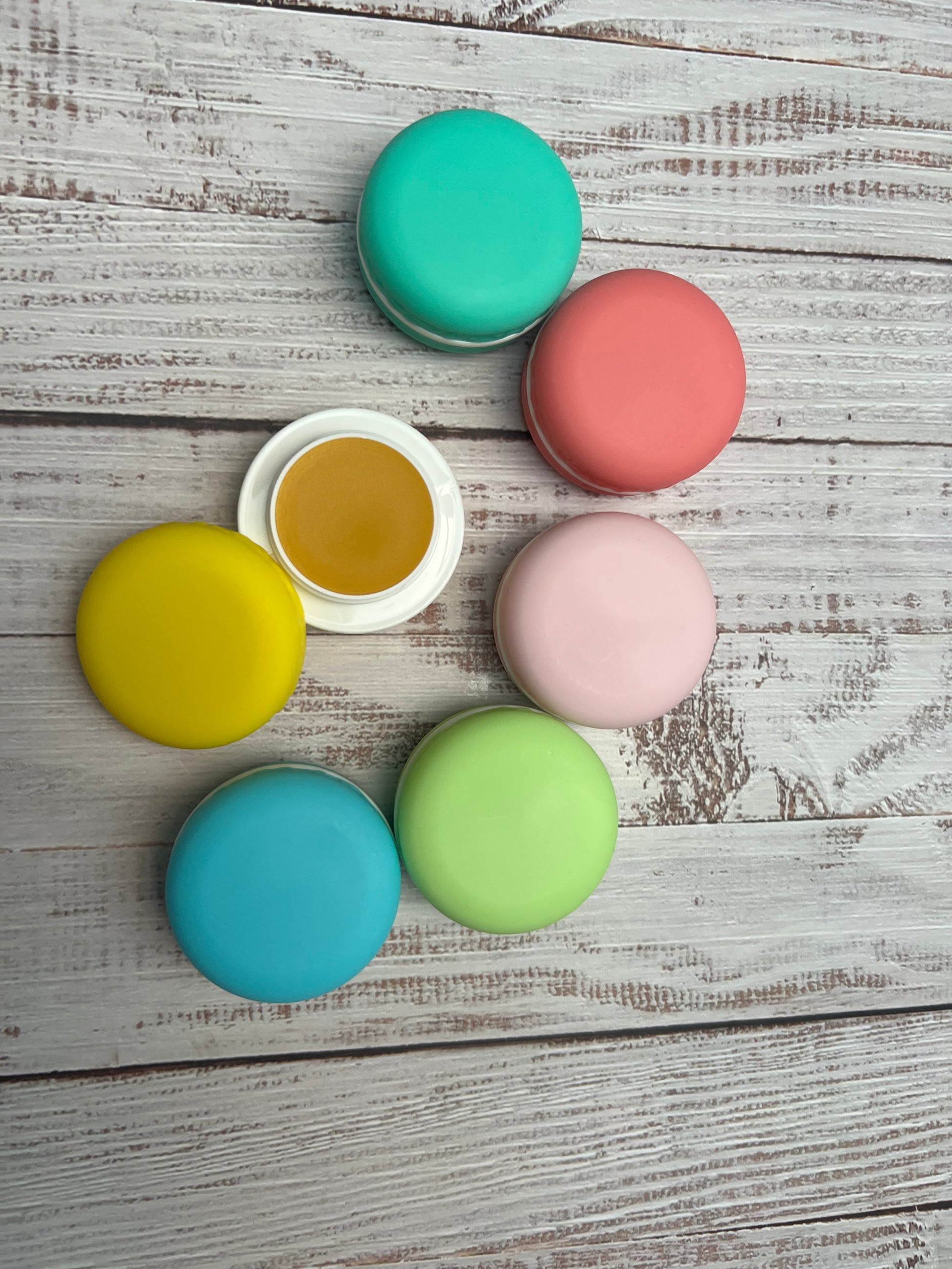 Close-up of a yellow macaron lip balm pot opened to reveal smooth golden balm.