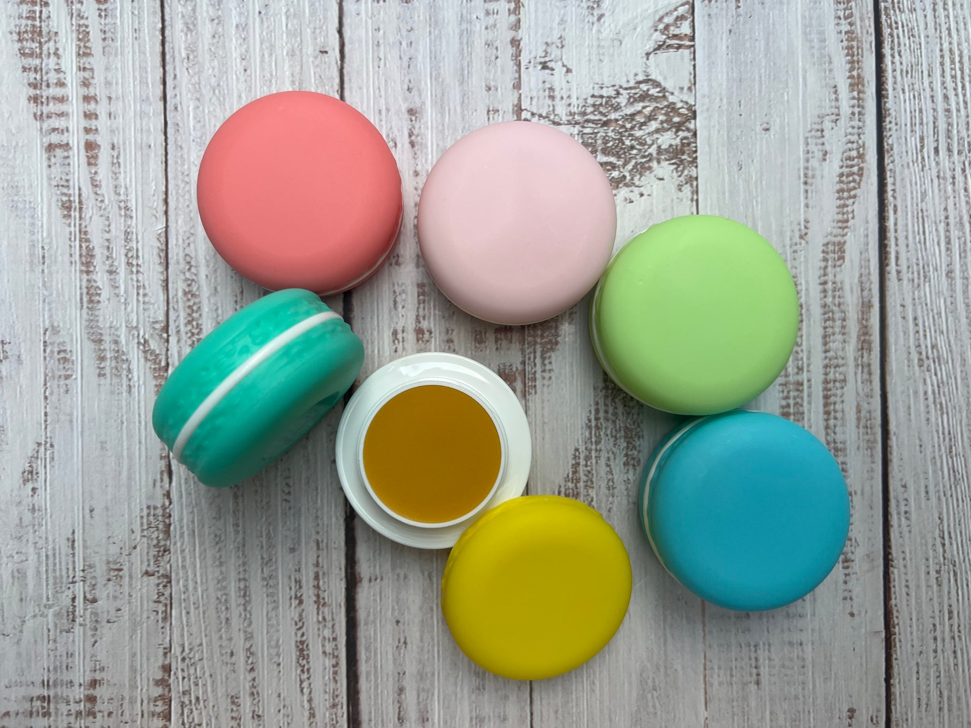 Colorful macaron cookies on a wooden surface filled with lip balm