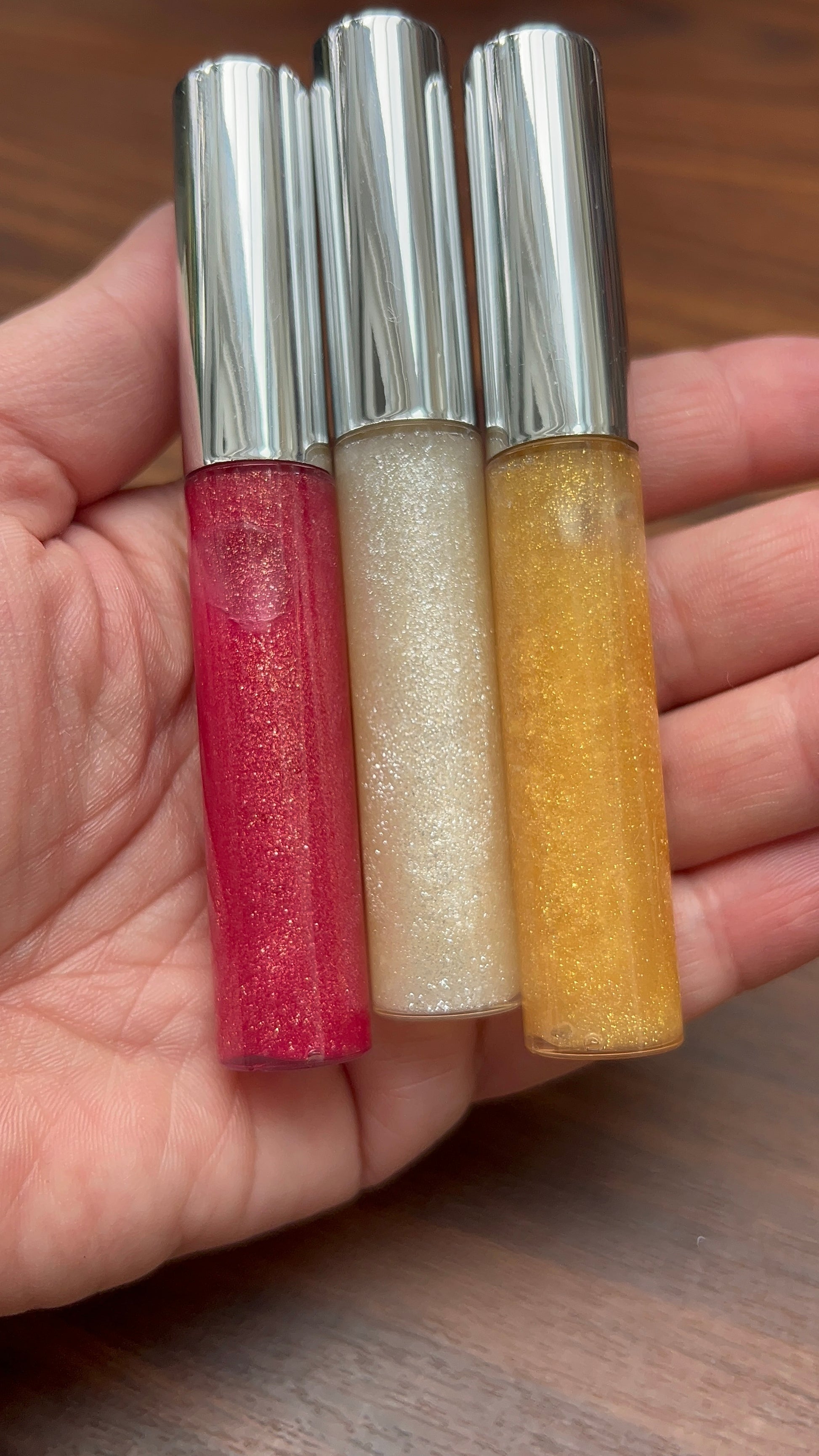 Trio of glitter roll-on bottles in red, white, and yellow with metallic caps