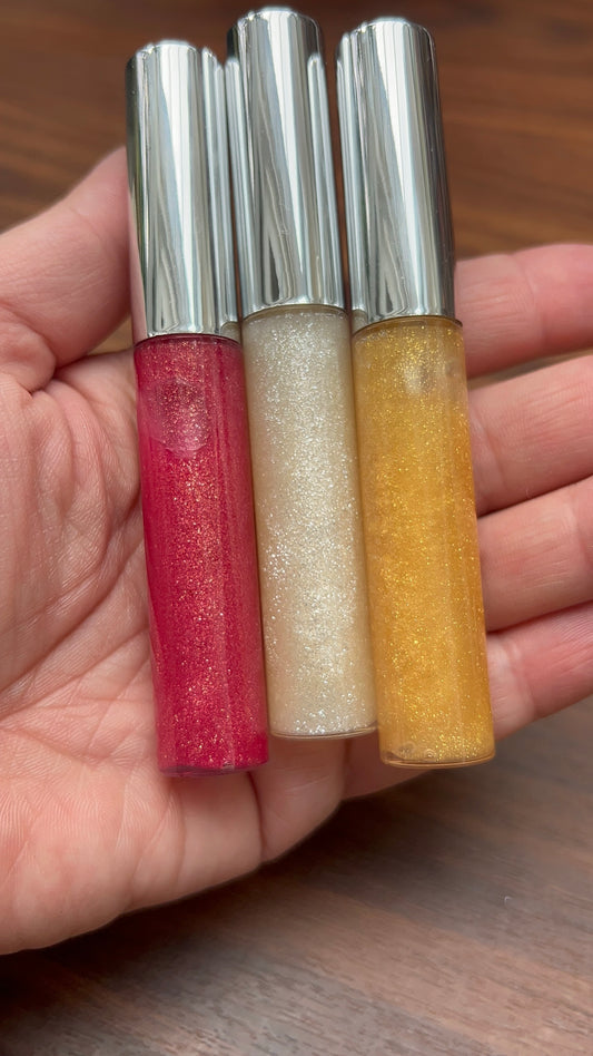 Trio of glitter roll-on bottles in red, white, and yellow with metallic caps