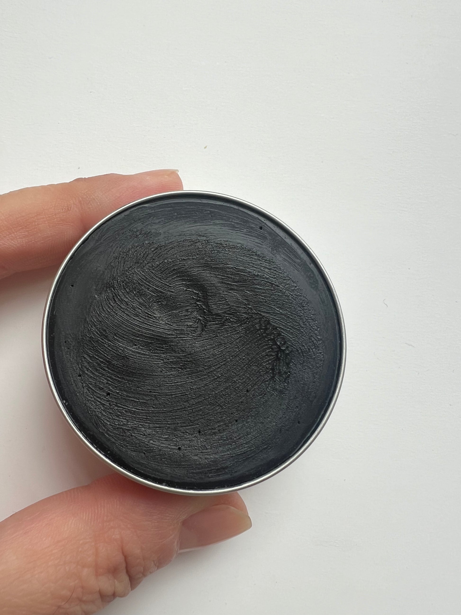 Top view of open tin containing natural activated charcoal deodorant.