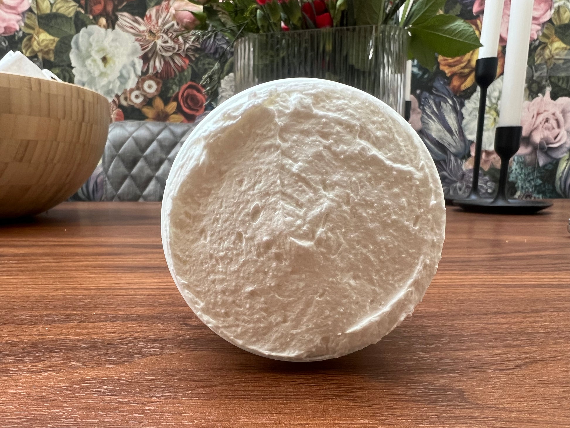 Open jar of whipped body butter placed on a wooden surface, showing its creamy texture.