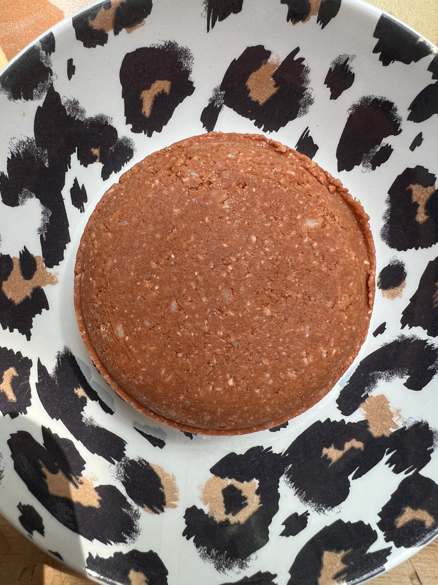 Red clay shampoo bar for deep cleansing on leopard print plate