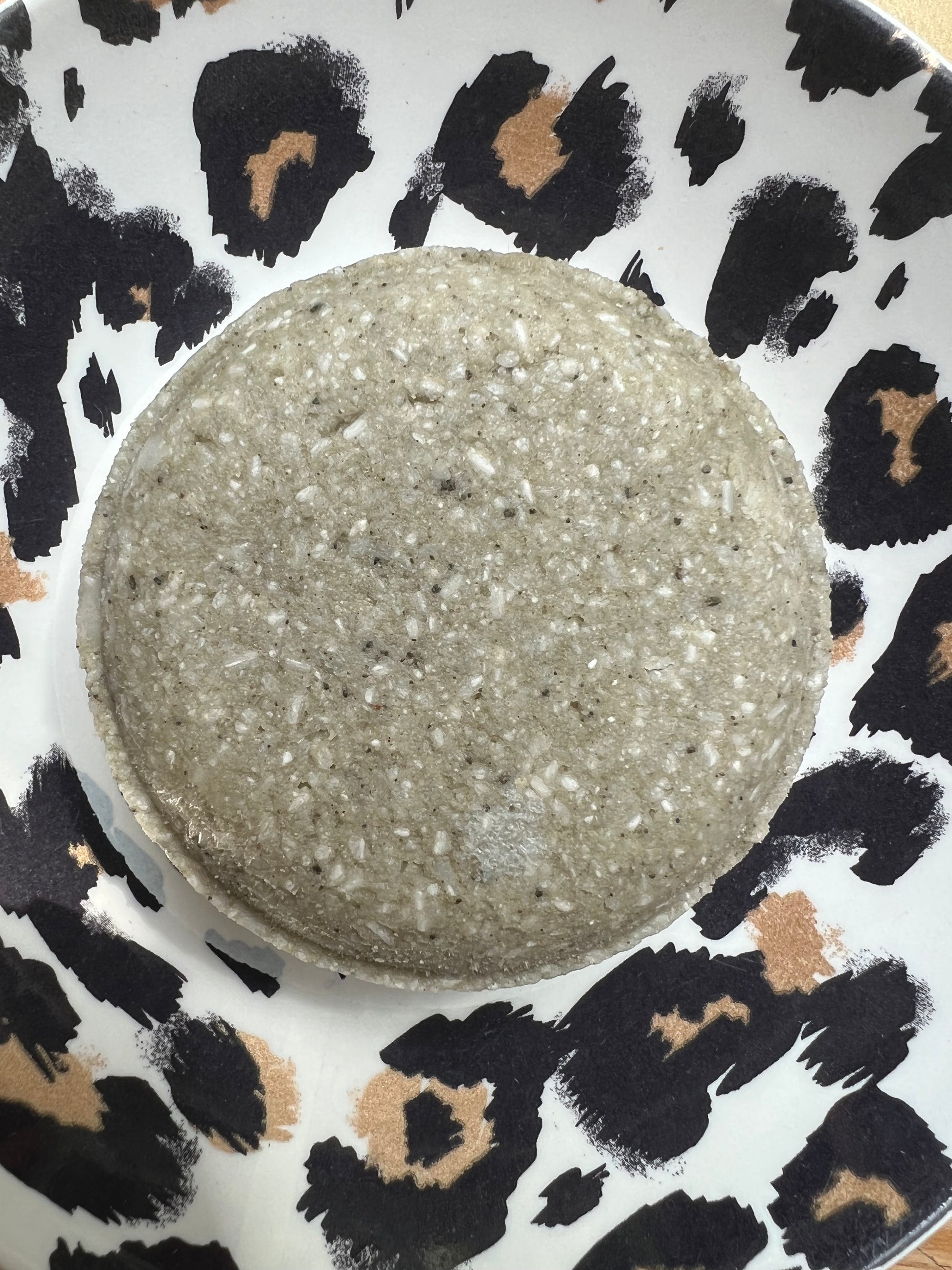 Green clay shampoo bar on patterned background