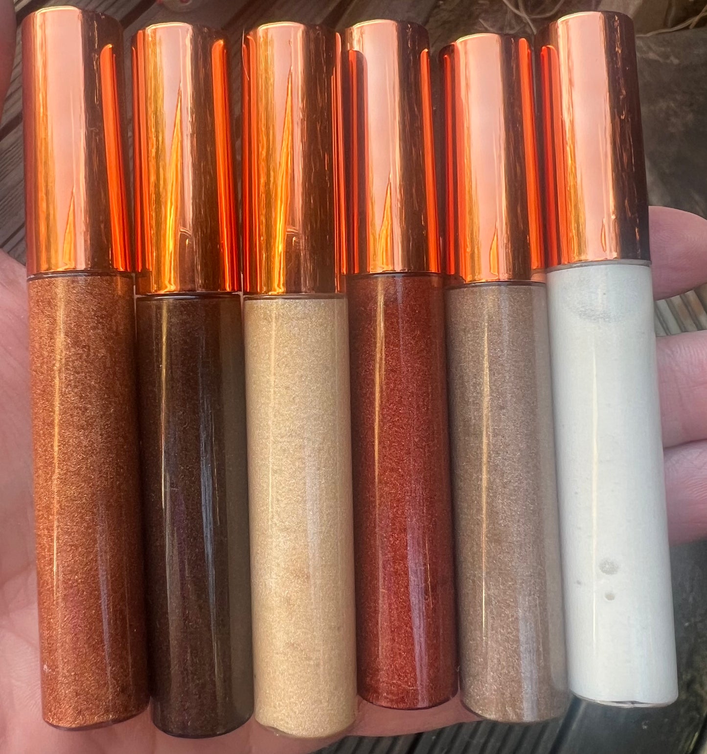 Bundle of 6 handmade natural lip glosses – bronze, gold, red, nude, and white shades – moisturizing, non-sticky, glossy finish.
