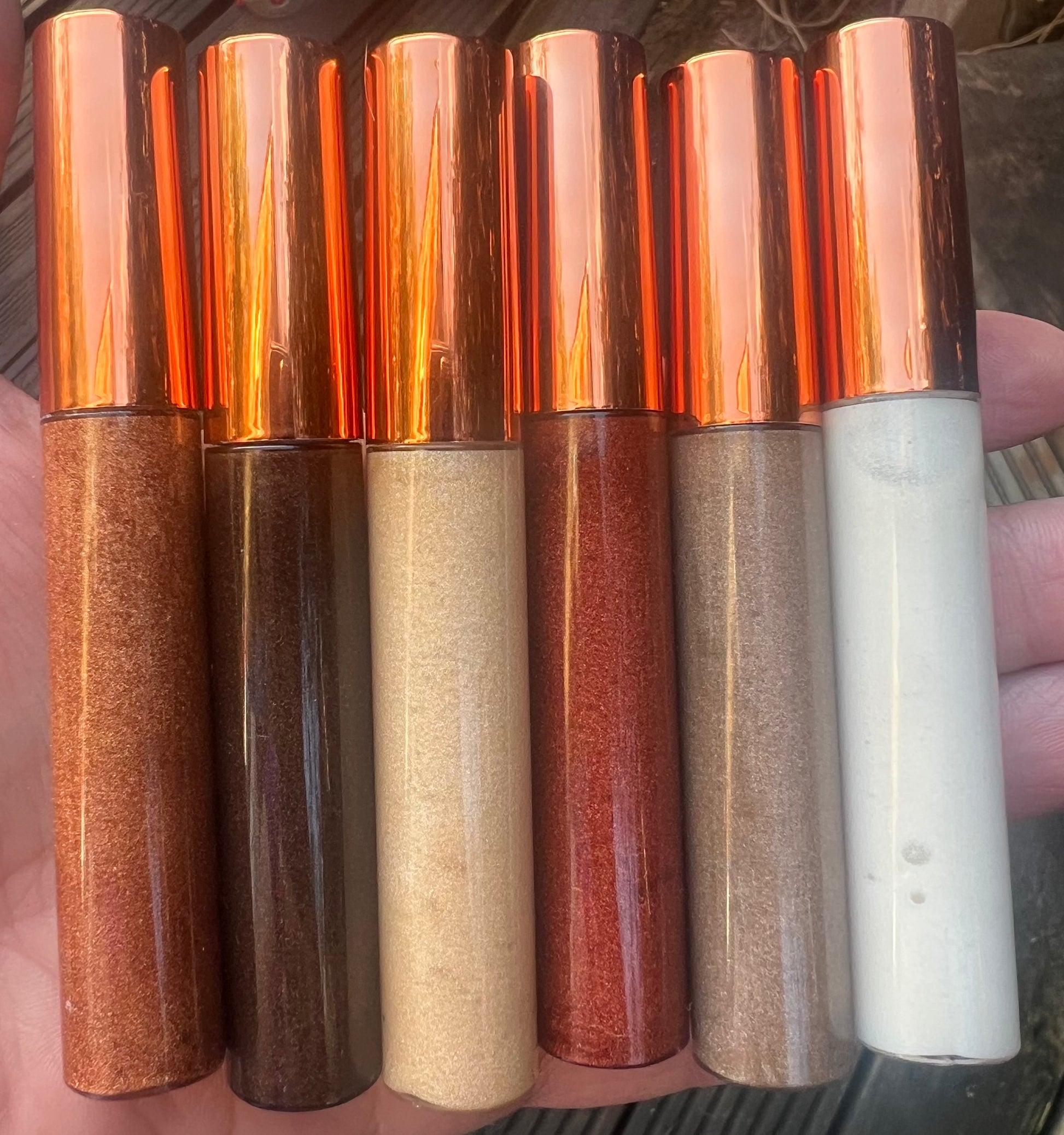 Bundle of 6 handmade natural lip glosses – bronze, gold, red, nude, and white shades – moisturizing, non-sticky, glossy finish.