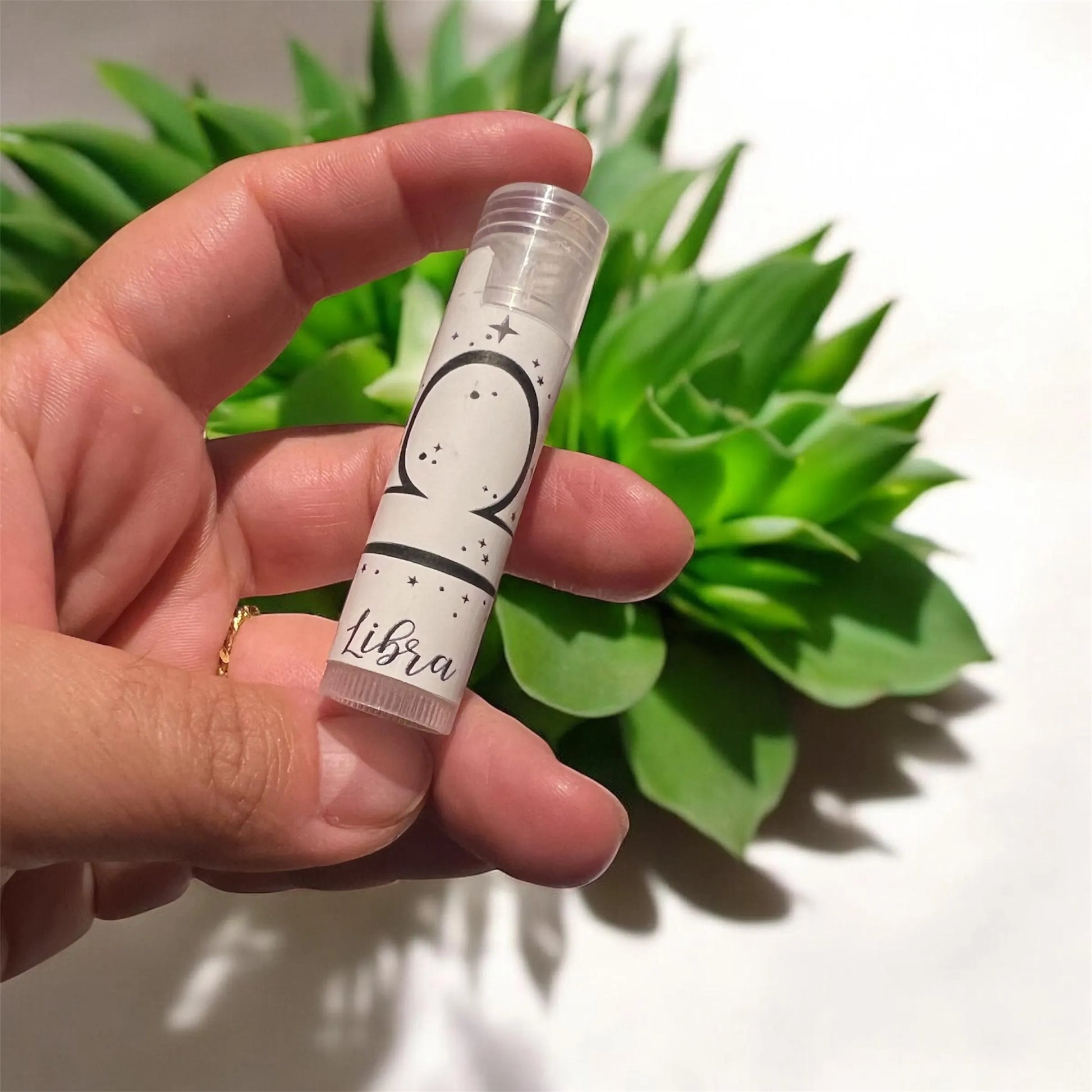 Close-up of hand holding vegan zodiac lip balm with astrology-inspired label
