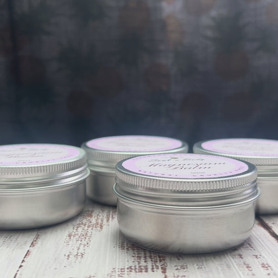 Metal tins of magnesium balm with white labels arranged on a wooden surface.