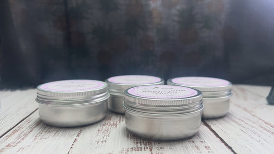 Metal tins of magnesium balm with white labels arranged on a wooden surface.